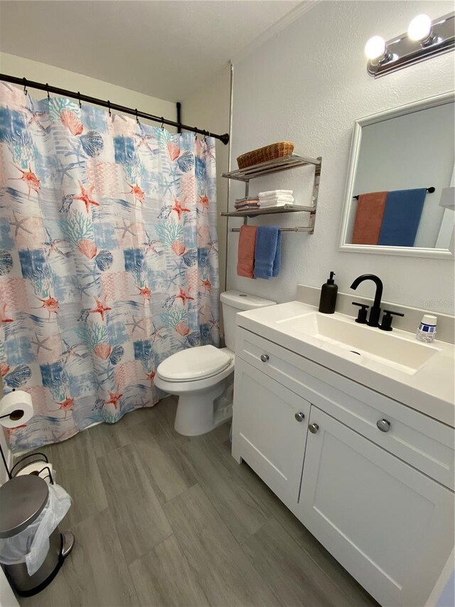 full bathroom with vanity, curtained shower, toilet, and a textured wall