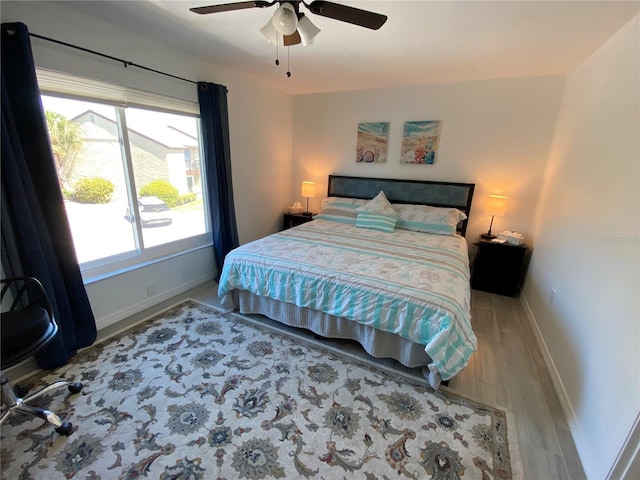 bedroom featuring light wood-style flooring, a ceiling fan, and baseboards