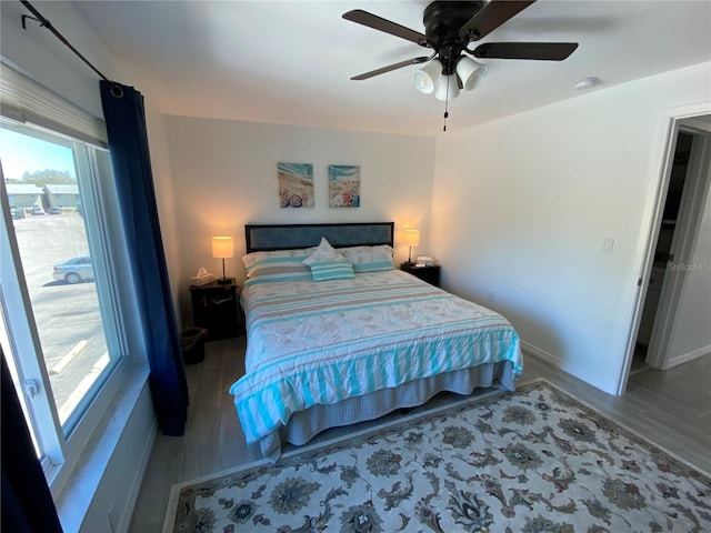 bedroom featuring baseboards, wood finished floors, and a ceiling fan