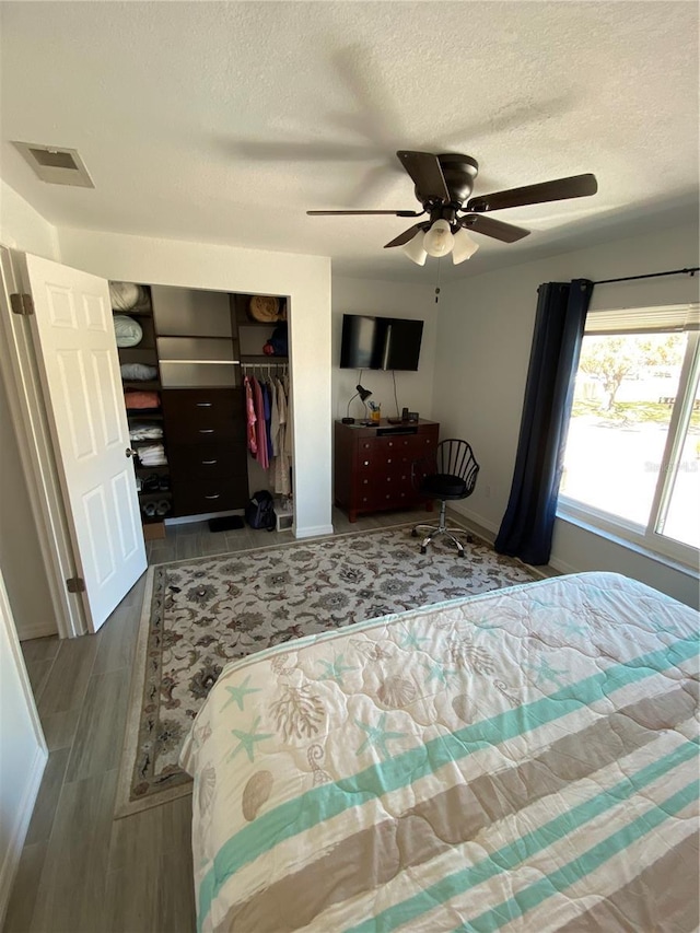 bedroom with visible vents, a textured ceiling, wood finished floors, a closet, and ceiling fan