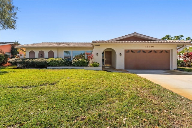 mediterranean / spanish-style house with a front yard, driveway, stucco siding, a garage, and a tile roof