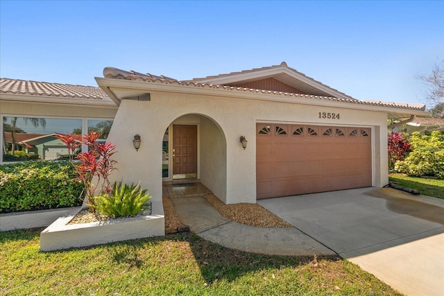 mediterranean / spanish-style house featuring a tiled roof, a garage, concrete driveway, and stucco siding