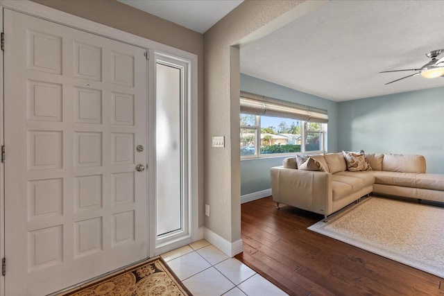 foyer with light tile patterned floors, baseboards, and a ceiling fan