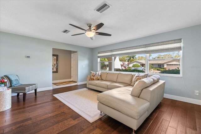 living room with a ceiling fan, dark wood-style floors, visible vents, and baseboards