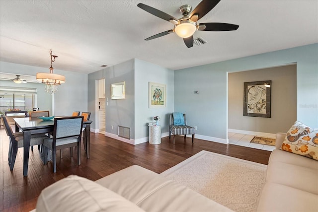 living room featuring visible vents, baseboards, hardwood / wood-style floors, and ceiling fan with notable chandelier