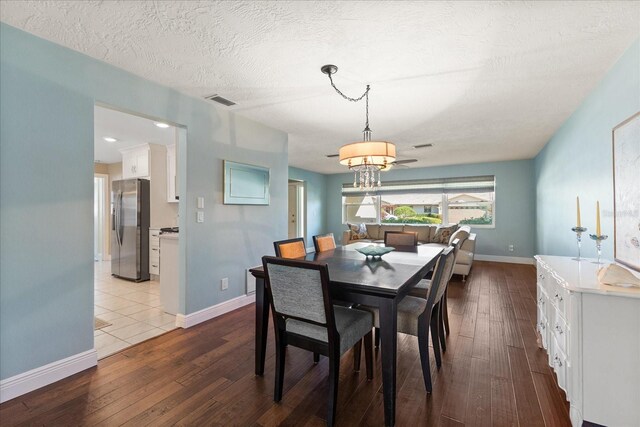 dining room featuring baseboards, visible vents, wood-type flooring, and an inviting chandelier