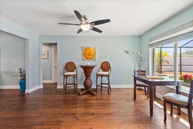 dining space featuring a textured ceiling, baseboards, ceiling fan, and hardwood / wood-style flooring