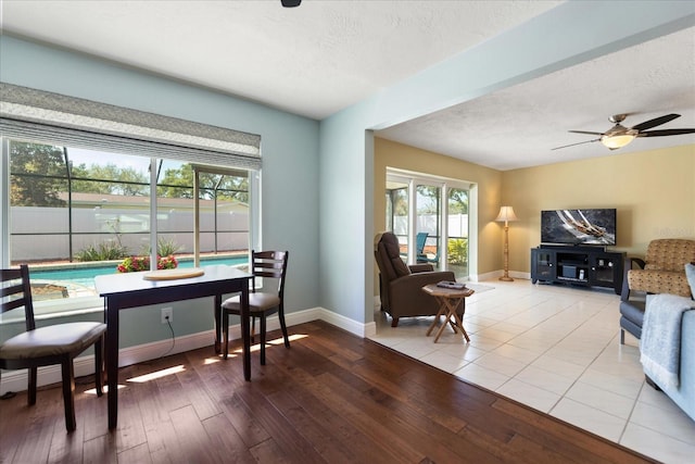 dining area featuring a textured ceiling, a ceiling fan, baseboards, and wood-type flooring