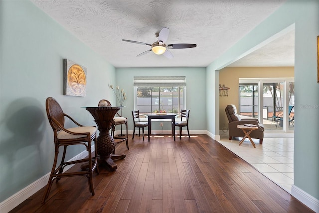 living area with plenty of natural light, a textured ceiling, ceiling fan, and dark wood-style flooring