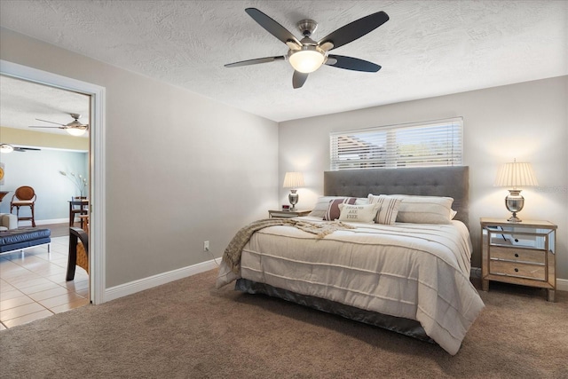 tiled bedroom featuring ceiling fan, carpet, baseboards, and a textured ceiling