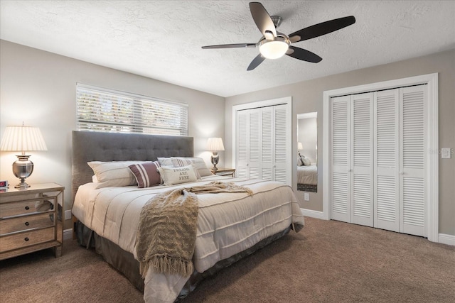 carpeted bedroom featuring baseboards, multiple closets, a textured ceiling, and a ceiling fan