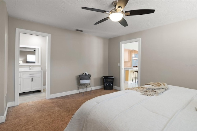 bedroom featuring visible vents, light carpet, a textured ceiling, connected bathroom, and baseboards