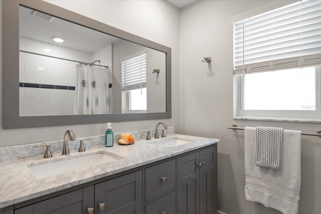 full bath featuring double vanity, plenty of natural light, and a sink