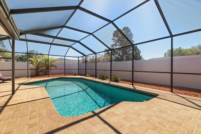 view of swimming pool featuring glass enclosure, a patio area, a fenced in pool, and a fenced backyard