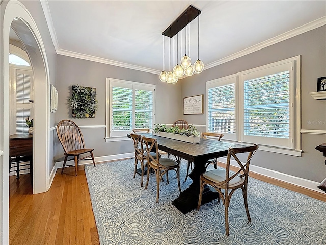 dining area featuring a notable chandelier, baseboards, light wood-style floors, and ornamental molding