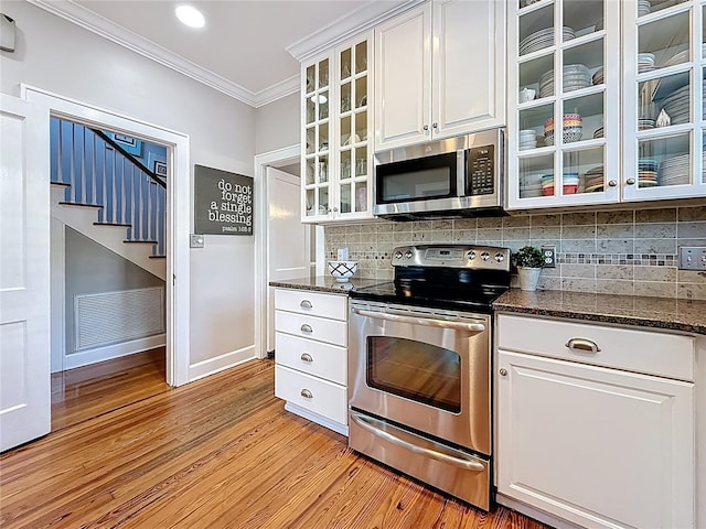 kitchen featuring visible vents, light wood-style flooring, appliances with stainless steel finishes, crown molding, and decorative backsplash