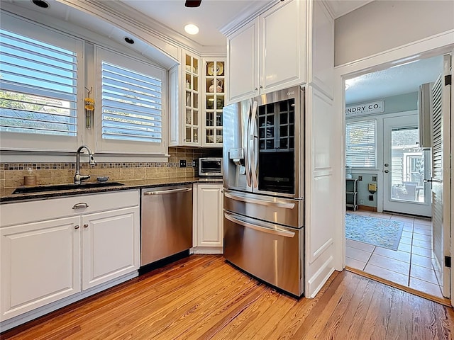 kitchen with a sink, tasteful backsplash, appliances with stainless steel finishes, and white cabinets