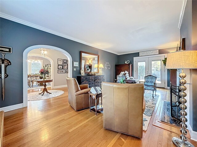 living room with arched walkways, light wood finished floors, and ornamental molding