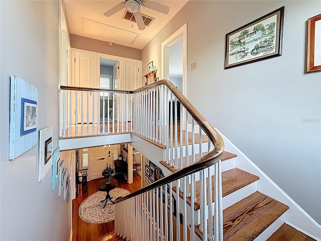 staircase with baseboards, attic access, ceiling fan, and wood finished floors