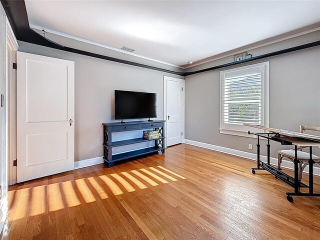 interior space featuring visible vents, baseboards, crown molding, and light wood finished floors