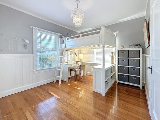 bedroom featuring a notable chandelier, wainscoting, ornamental molding, and wood finished floors