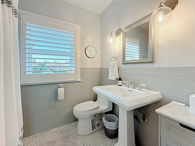 bathroom featuring toilet, tile walls, wainscoting, and tile patterned flooring