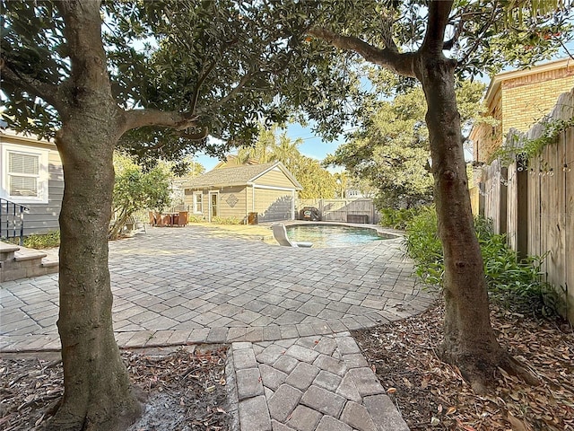 view of patio / terrace with an outdoor structure, a storage structure, a fenced backyard, and a fenced in pool