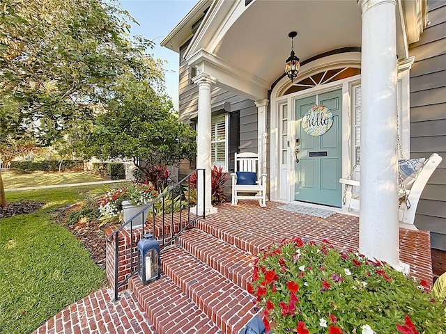 view of exterior entry with covered porch and a yard