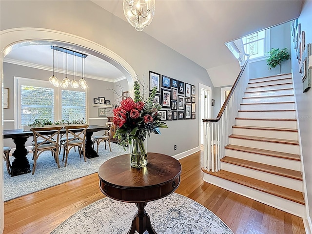 foyer with hardwood / wood-style floors, stairway, baseboards, arched walkways, and ornamental molding