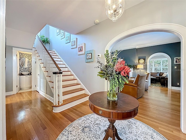 stairway with hardwood / wood-style flooring, baseboards, and arched walkways