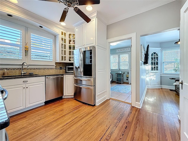 kitchen with ceiling fan, decorative backsplash, a sink, appliances with stainless steel finishes, and white cabinetry