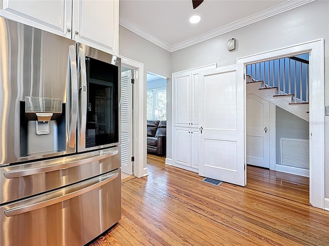 kitchen with visible vents, ornamental molding, light wood-style flooring, white cabinets, and stainless steel fridge