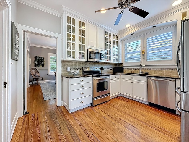 kitchen with crown molding, decorative backsplash, light wood-style floors, stainless steel appliances, and a sink