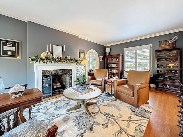 living area with wood finished floors, ornamental molding, and a high end fireplace