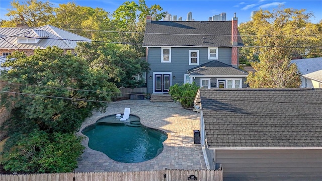 back of house with a fenced in pool, roof with shingles, a chimney, entry steps, and a patio area