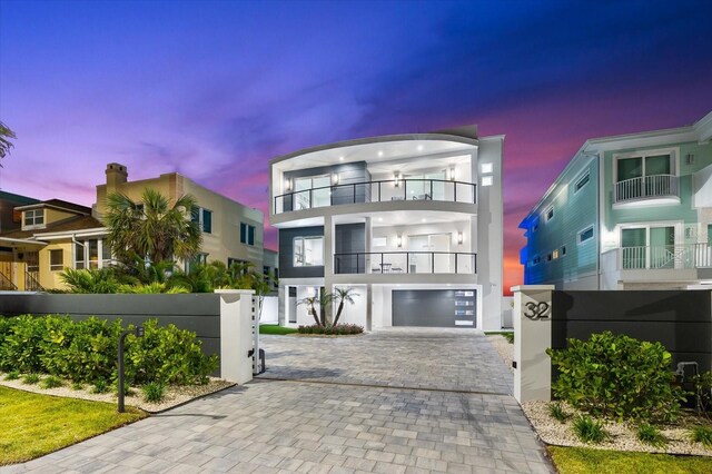 32 Gulf Blvd, Indian Rocks Beach, FL 33785 - view of front of house with a balcony, a gate, decorative driveway, stucco siding, and a garage