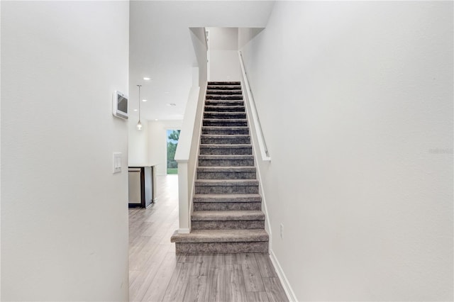 staircase with recessed lighting, baseboards, and wood finished floors