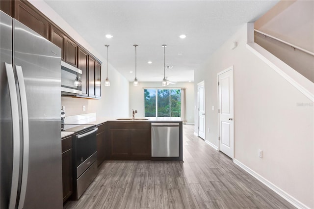 kitchen with a ceiling fan, a peninsula, light wood-style flooring, dark brown cabinets, and appliances with stainless steel finishes