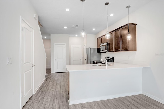 kitchen featuring light wood finished floors, visible vents, dark brown cabinetry, appliances with stainless steel finishes, and a sink