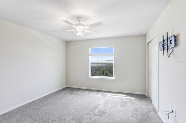 unfurnished bedroom with baseboards, carpet flooring, a closet, a textured ceiling, and a ceiling fan