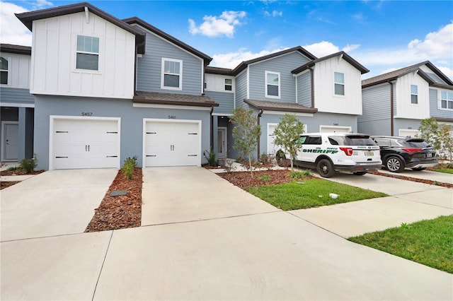 multi unit property featuring board and batten siding, concrete driveway, roof with shingles, stucco siding, and an attached garage