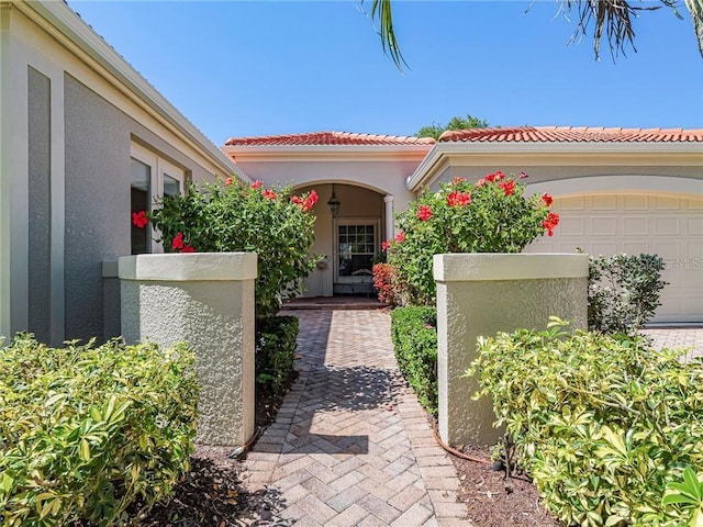 exterior space featuring a tile roof, an attached garage, and stucco siding