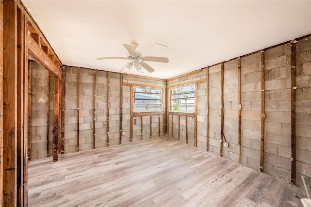 unfurnished room with ceiling fan, wood finished floors, and concrete block wall