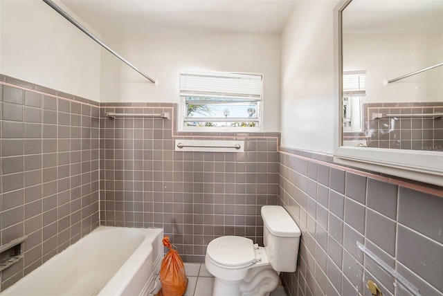 bathroom with a wealth of natural light, toilet, tile walls, and tile patterned flooring