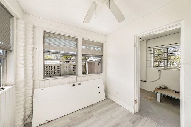 interior space with baseboards, ceiling fan, and wood finished floors