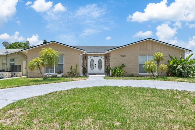 ranch-style house with a front yard, brick siding, and central AC