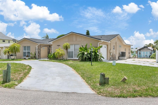 single story home featuring a residential view, a front yard, central AC, driveway, and an attached garage