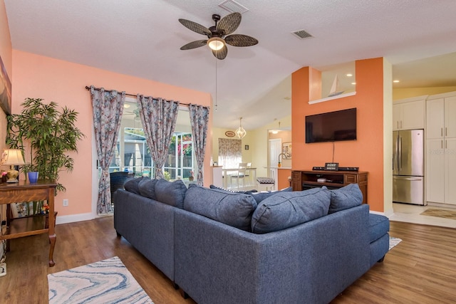 living area with vaulted ceiling, visible vents, ceiling fan, and wood finished floors