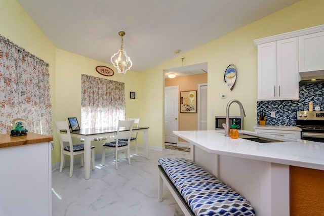 kitchen with vaulted ceiling, stainless steel electric range, an inviting chandelier, marble finish floor, and a sink