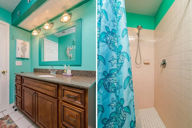 bathroom with vanity, tile patterned floors, a tile shower, and a textured ceiling